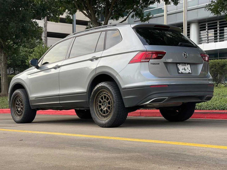 Lifted VW Tiguan with roof rack, all-terrain tires, and off-road armor parked on dirt trail in backcountry terrain