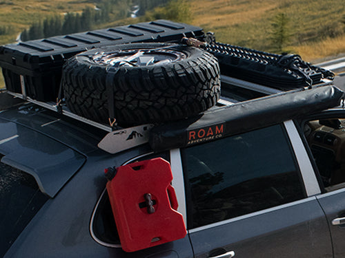 Porsche Cayenne outfitted with roof rack and cargo gear on mountain trail, loaded for overlanding