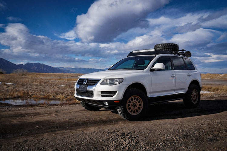 Lifted VW Touareg equipped with off-road bumpers, roof rack, and skid plates on rugged mountain trail