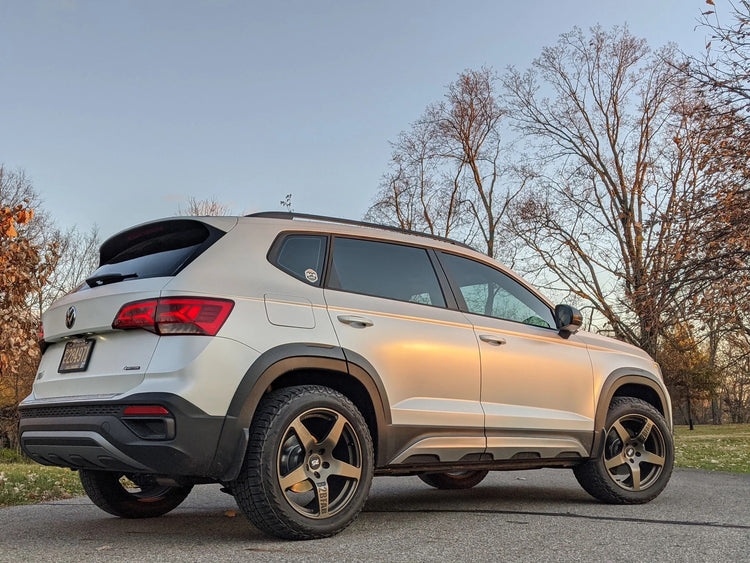 Lifted VW Taos with roof rack, all-terrain tires, and skid plates climbing rocky mountain trail